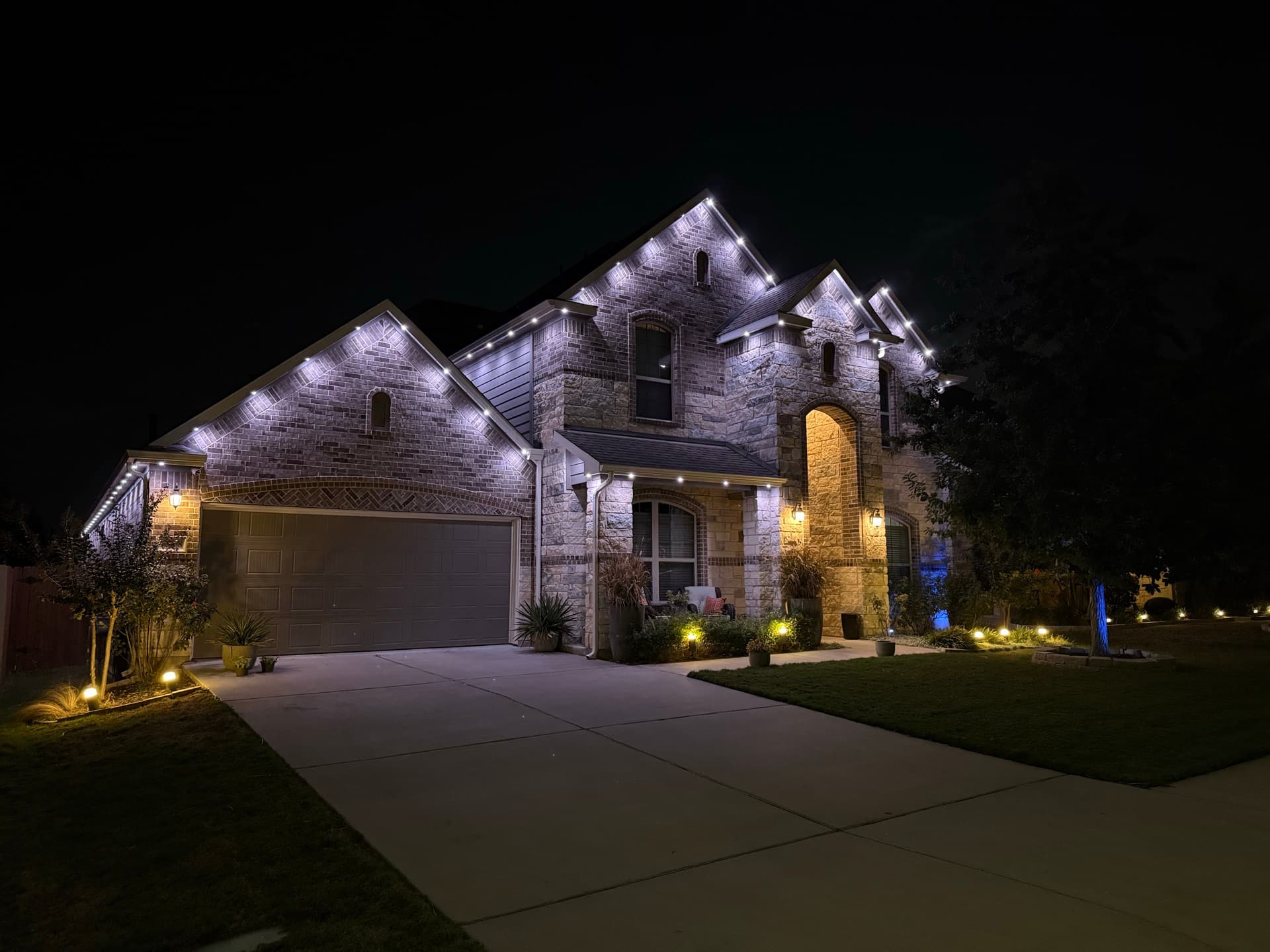 Professional permanent lighting installation on an Austin limestone ranch home