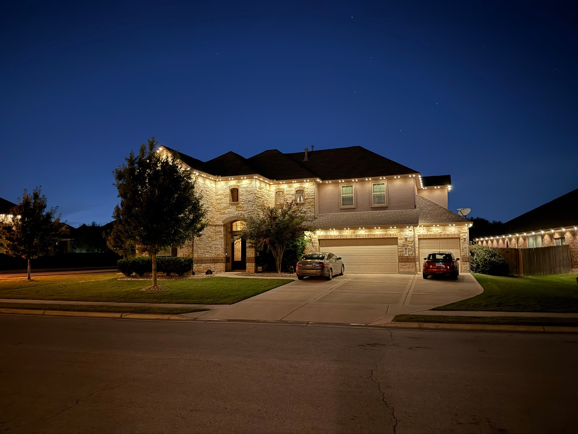 Permanent warm white lighting adding curb appeal to an Austin home at dusk