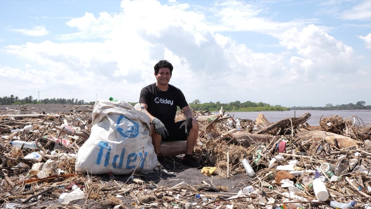 Tidey Ocean founder at a beach covered in plastic debris