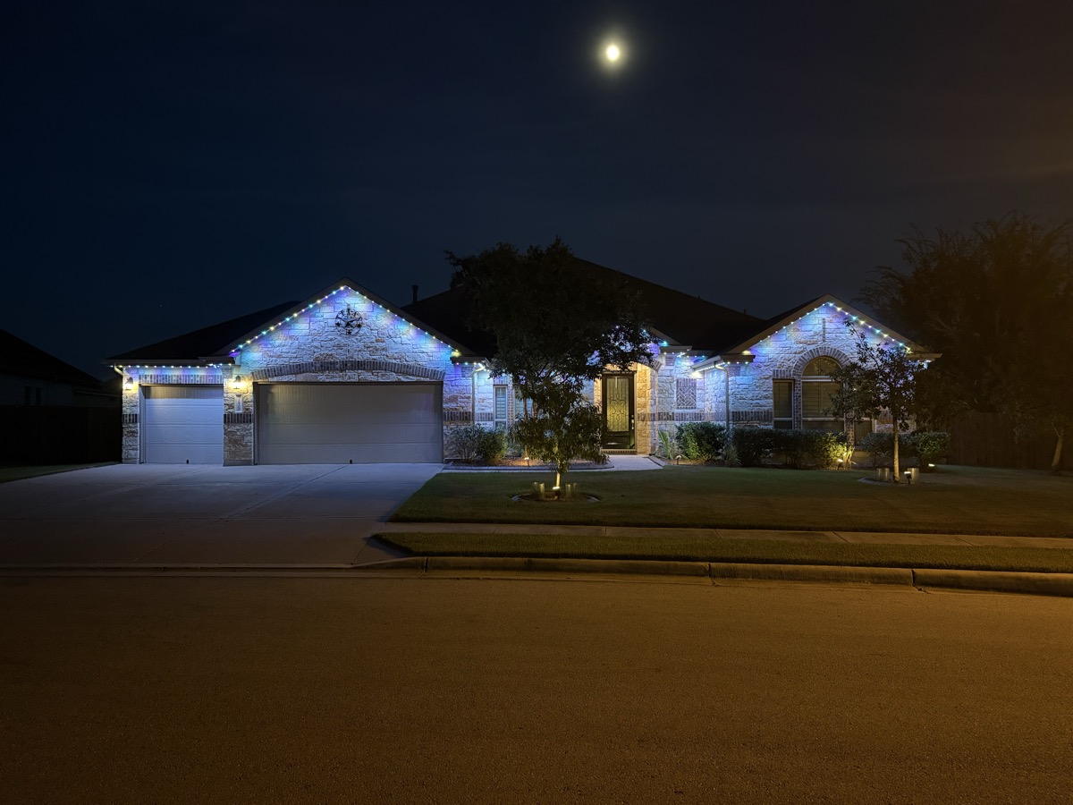 Low-profile permanent lighting track on an Austin home roofline during daytime