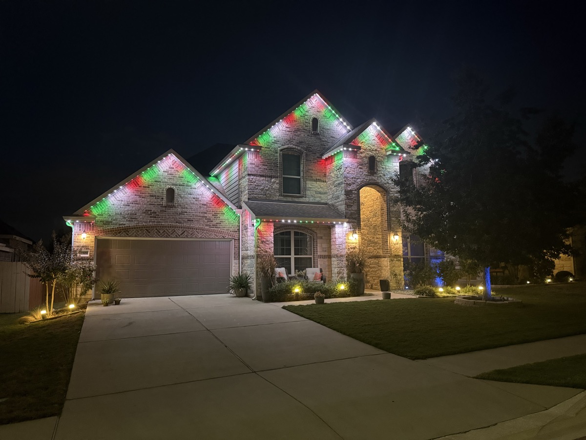 RGBW permanent lighting accenting limestone and stucco on a large Austin home at night