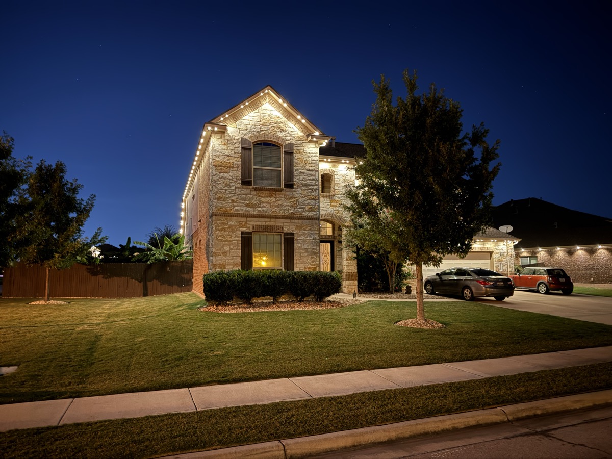Permanent warm white lighting adding curb appeal to an Austin home at dusk
