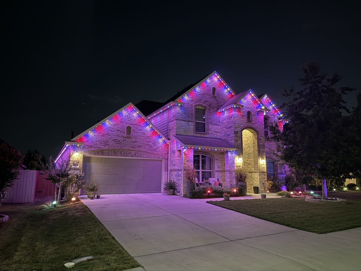 Large Austin stone home with permanent warm white LED roofline lighting at night